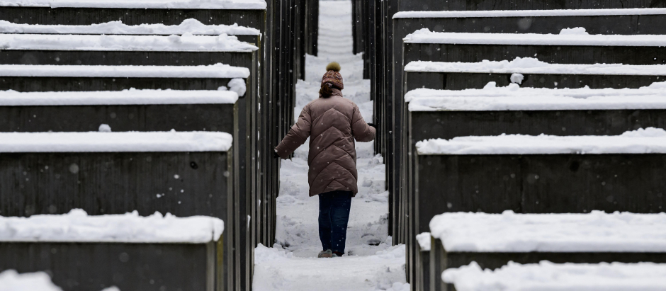 Un visitante camina entre las estelas cubiertas de nieve del monumento al Holocausto mientras nieva en Berlín