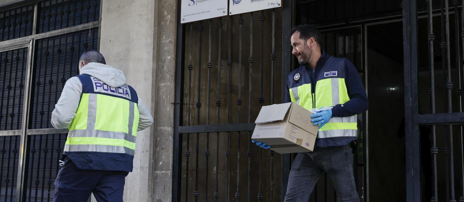 Agentes de la Policía Nacional portan objetos del domicilio del canónigo asesinado en Valencia