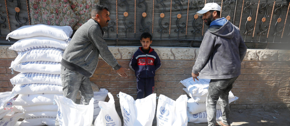 Gazatíes junto a sacos de comida de la UNRWA