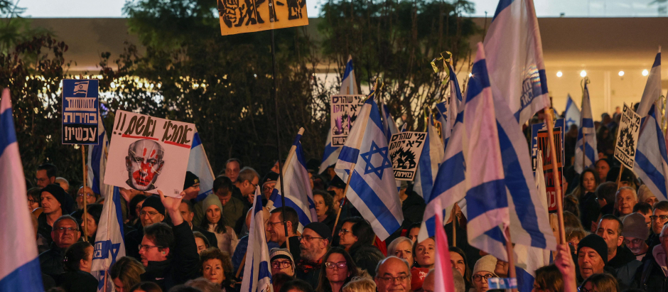 Los manifestantes levantan banderas nacionales y pancartas durante una manifestación en la ciudad central de Tel Aviv,