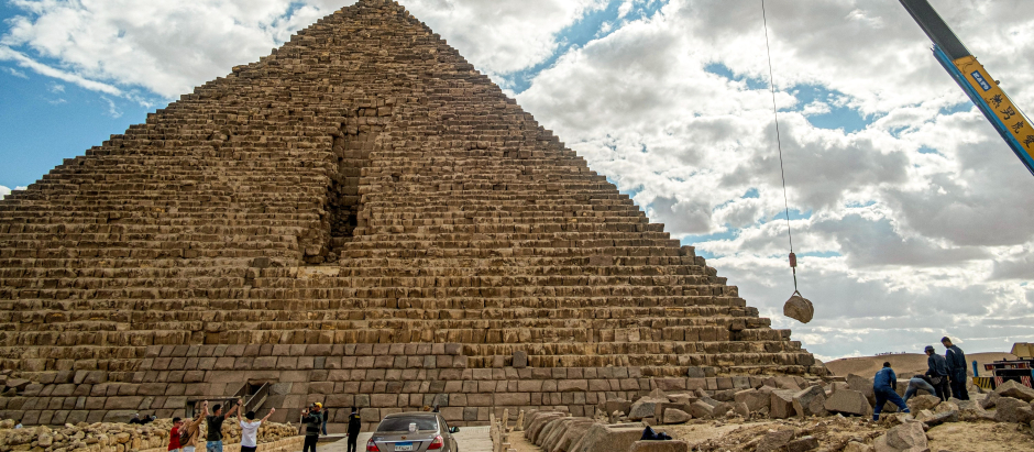 Una grúa levanta una piedra durante un proyecto de conservación junto a la base de la Pirámide de Micerino