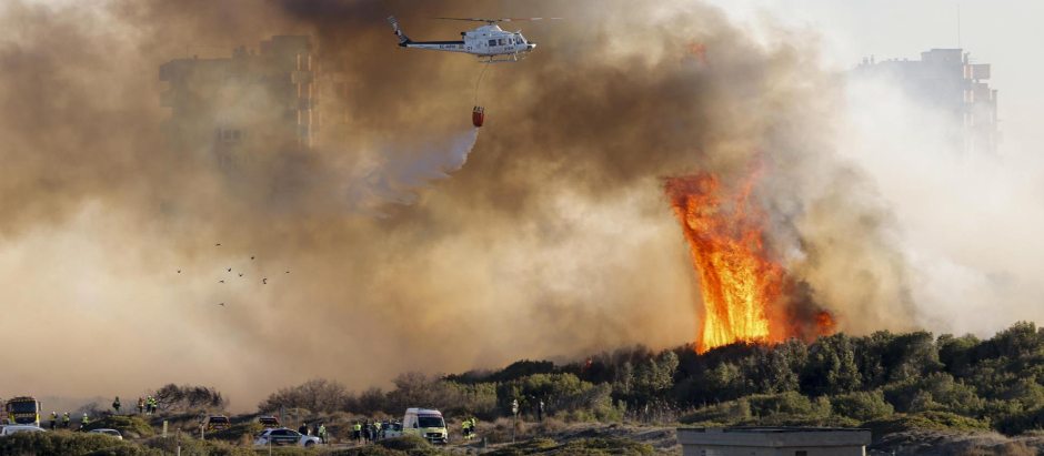 Un helicóptero trabaja en las labores de extinción del incendio forestal declarado a primera hora de la tarde de este lunes en El Saler, en Valencia