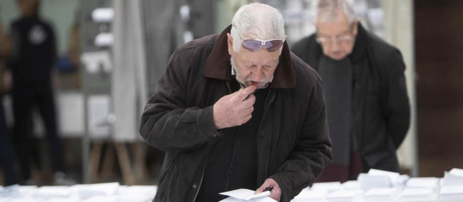 Un hombre escoge papeleta para ejercer su derecho al voto en un colegio electoral en Vigo, durante la jornada electoral este domingo
