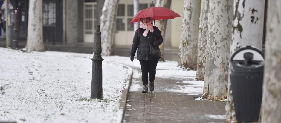 Una mujer sujeta un paraguas mientras camina por una calle de nieve en Jaca, Huesca