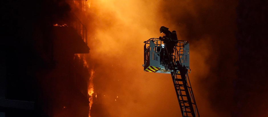 Un bombero trata de apagar el edificio en llamas en el barrio valenciano de Campanar