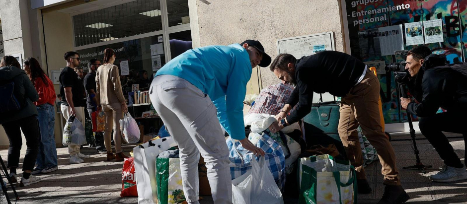 Varios valencianos, recogiendo y repartiendo mantas y otros objetos donados por vecinos a las víctimas del incendio