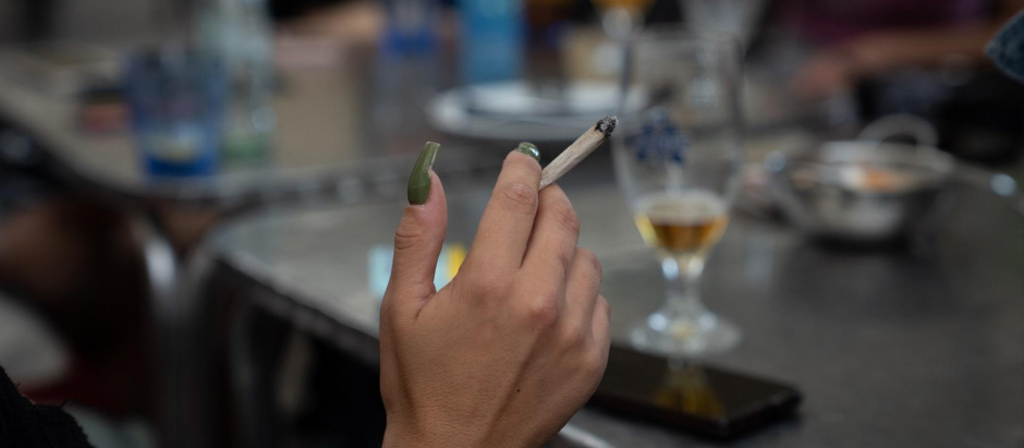 Una mujer fuma sentada en la mesa de una terraza