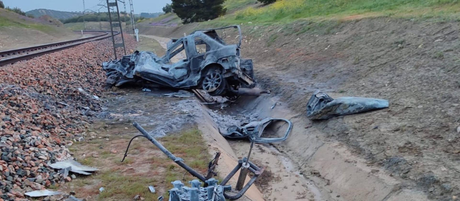 Restos del vehículo quemado en la vía del tren entre Jaén y Espeluy
