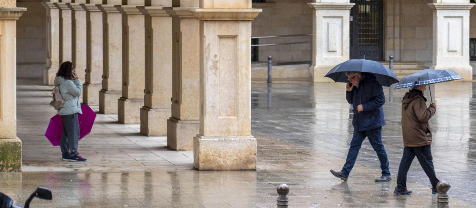 Varias personas con paraguas caminan mientras llueve este lunes, en Teruel