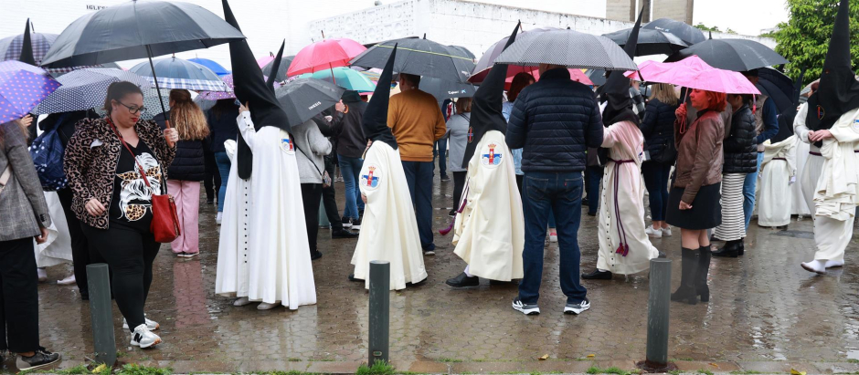 Nazarenos de la Hermandad de San Pablo, bajo la lluvia en Sevilla