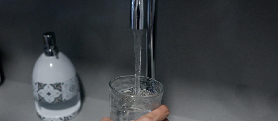 Una persona llena un vaso de agua de un grifo