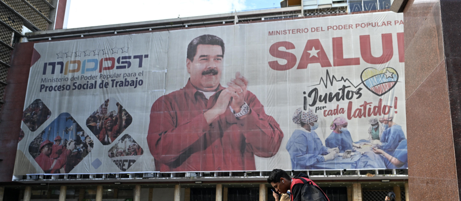 La gente camina frente a una enorme pancarta que representa al presidente venezolano, Nicolás Maduro, en Caracas