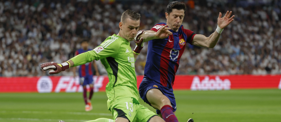 El guardameta ucraniano del Real Madrid Andriy Lunin (i) disputa un balón con el delantero polaco del FC Barcelona Robert Lewandowski
