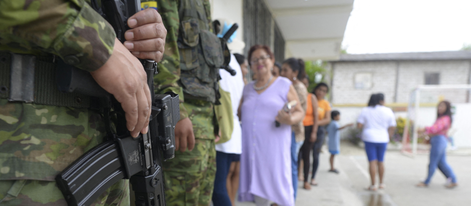 Los soldados hacen guardia mientras la gente hace cola para votar en un colegio electoral, en Ecuador
