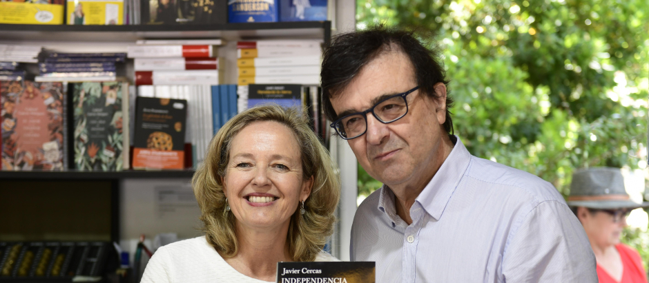 Nadia Calviño (i), conversa con el escritor Javier Cercas (d) durante su visita a la Feria del Libro en el Retiro, en Madrid
