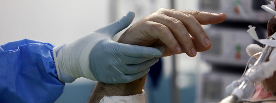 Un médico sostiene la mano de un enfermo