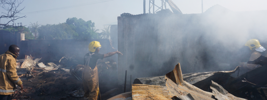 Los bomberos trabajan junto a los restos quemados de la explosión en Freetown
