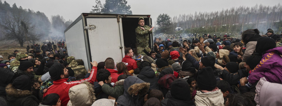 Inmigrantes se reúnen para obtener ayuda humanitaria difundida por militares bielorrusos en el campamento en la frontera entre Bielorrusia y Polonia en la región de Grodno