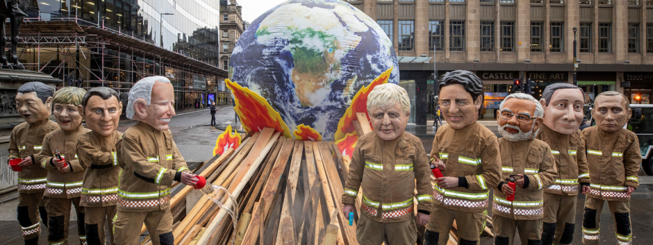 Un grupo de activistas mientras posan como líderes mundiales disfrazados de bomberos este viernes durante el último día de la COP26