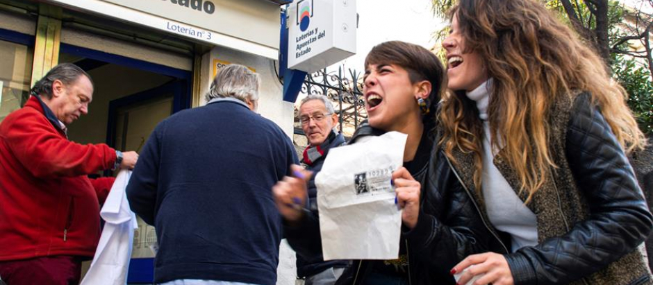 Un grupo de personas celebran en San Lorenzo de El Escorial el segundo premio de la Lotería de Navidad en 2019