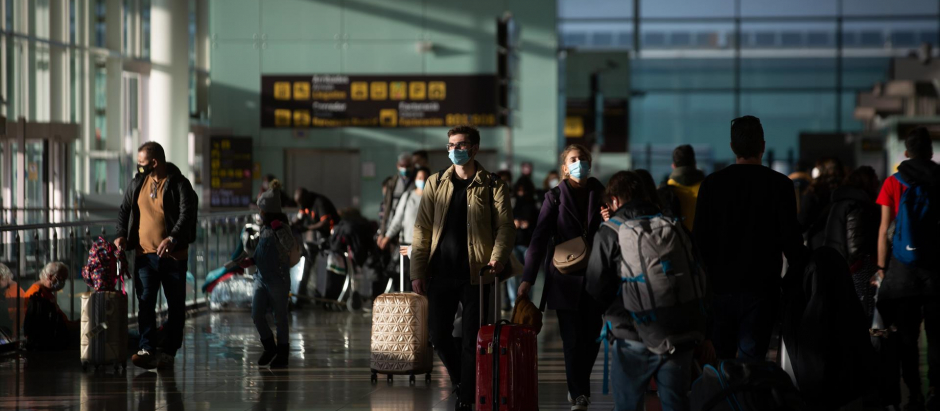 Varios pasajeros con maletas en el aeropuerto de El Prat, en Barcelona