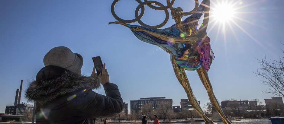 Una mujer fotografía una escultura de una pareja de patinaje artístico con motivo de los Juegos Olímpicos de Invierno 2022 en el parque industrial Shougang en Pekín