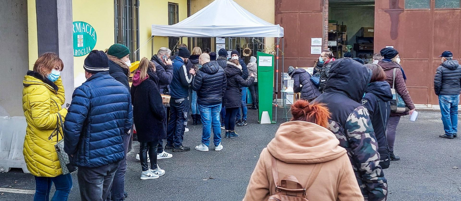 Un grupo de personas hace cola frente a una farmacia de Turín, Italia, para someterse a un test covid de antígenos