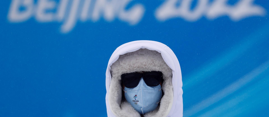 Un voluntario se protege del frío en el parque de nieve Genting, cerca de la sede de los Juegos Olímpicos de Invierno Pekín 2022