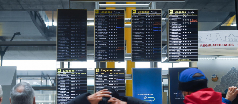 Varias personas observan los paneles de llegadas en el aeropuerto de Adolfo Suárez