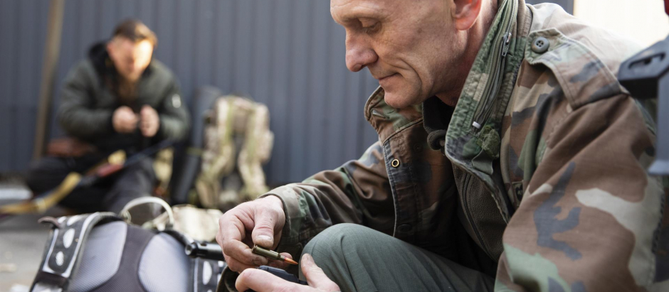 Un combatiente de defensa territorial reciben armas y municiones en Kiev, Ucrania