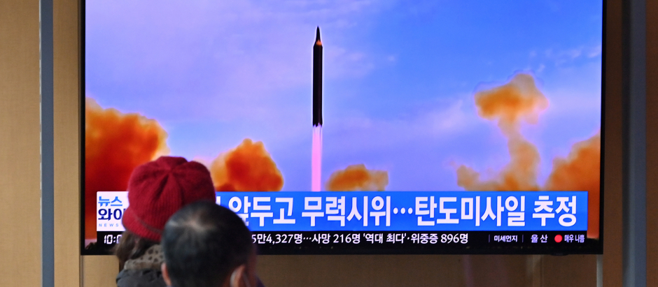 La gente mira una pantalla de televisión que muestra una transmisión de noticias con imágenes de archivo de una prueba de misiles de Corea del Norte