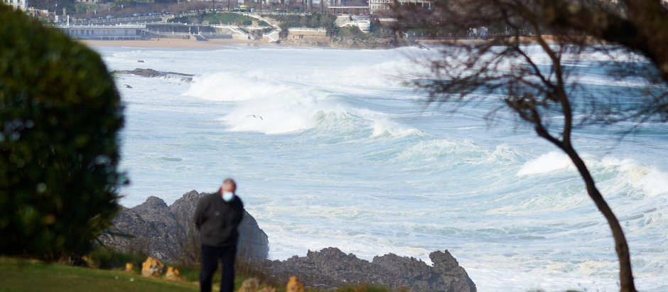 Una persona camina cerca de la playa donde se puede observar el fuerte oleaje en Santander (Cantabria).