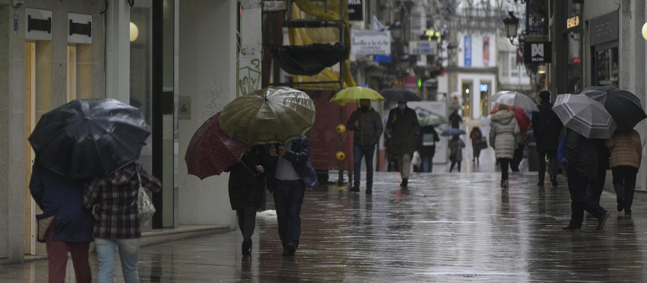 Transeúntes caminando por la calle Real de La Coruña un día de lluvia
