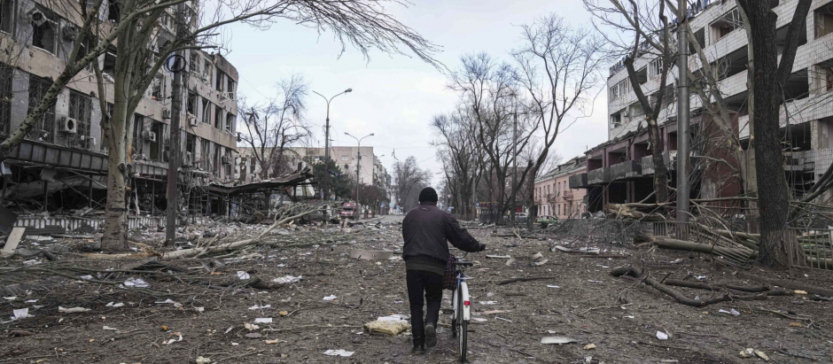 Un habitante de Mariúpol (Ucrania) camina con su bici por las calles devastadas de la ciudad