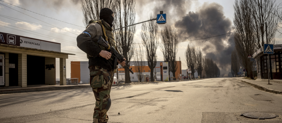 Un militar ucraniano hace guardia cerca de un almacén en llamas alcanzado por un proyectil ruso en los suburbios de la capital, Kiev