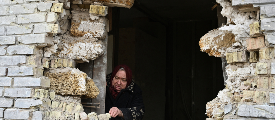 Una mujer ucraniana se asoma al boquete provocado por los ataques de Rusia en la pared de su casa