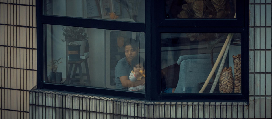 Una mujer con un bebé en cuarentena miran este miércoles por la ventana de su apartamento en medio del confinamiento por el coronavirus en la ciudad de Shanghái, China. Según la Comisión de Salud de Shanghái el 27 de abril había 48 nuevas muertes por coronavirus, 1.606 casos transmitidos y 11.956 personas infectadas asintomáticas