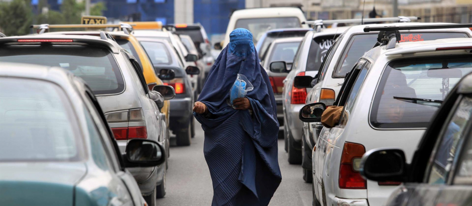 Una mujer con burka camina entre los coches en Afganistán