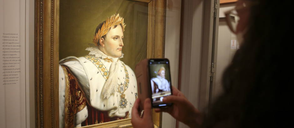 Una mujer saca una fotografía de uno de los cuadros más famosos de Napoleón Bonaparte en una exposición dedicada al emperador francés en su casa natal