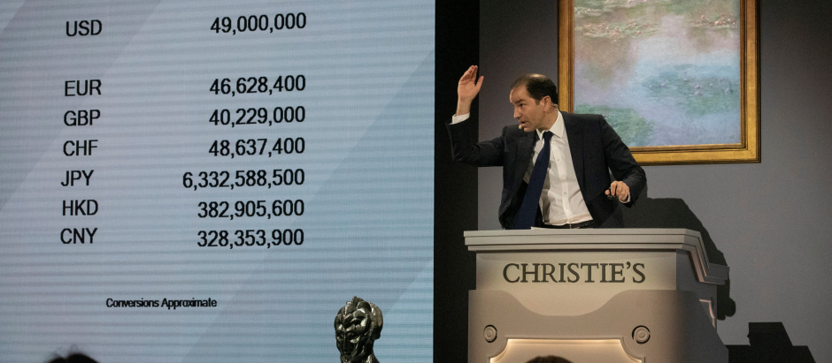 New York (United States), 13/05/2022.- Christie's auctioneer ends the auction of 'Nympheas' by Claude Monet, displayed behind him, for $49 million dollars at the gavel, during an Evening Sale of works from The Collection of Anne H. Bass, at Christie's Auction House in New York, New York, USA, 12 May 2022. (Estados Unidos, Nueva York) EFE/EPA/SARAH YENESEL