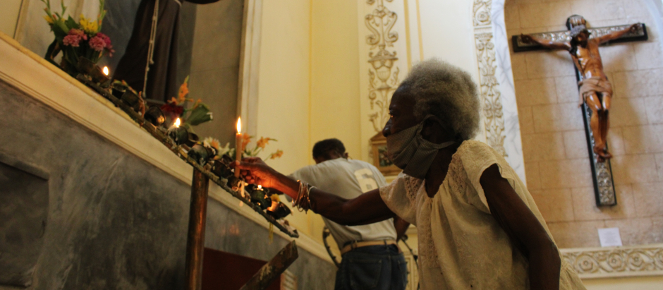 Una mujer cubana pone una vela ante la imagen de san Francisco de Asís, en una iglesia de La Habana