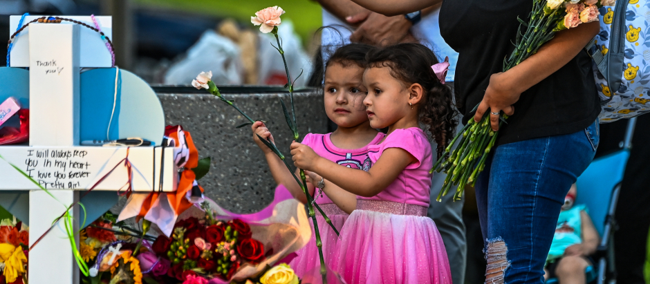 Una mujer deposita flores junto a su hija en un monolito improvisado en Uvalde, Texas, donde se produjo la masacre en un colegio