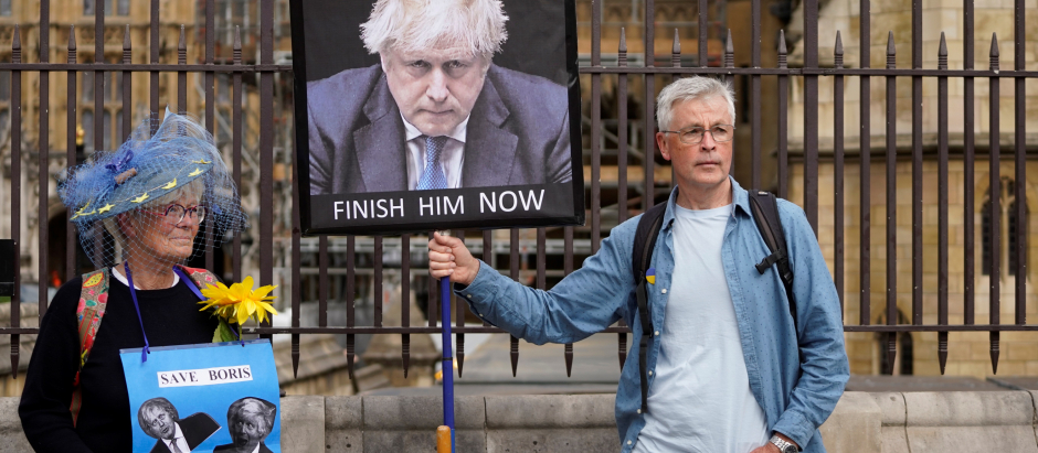 Los manifestantes sostienen pancartas que representan al primer ministro británico, Boris Johnson, frente a la Cámara del Parlamento, en Londres