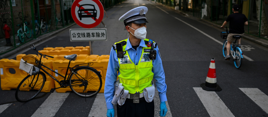 Un policía vigila una calle al lado de un área residencial bajo bloqueo de Covid-19 en el distrito Xuhui de Shanghai