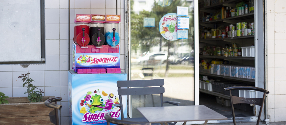Un comercio francés con una máquina de venta de granizados en su exterior y la puerta abierta