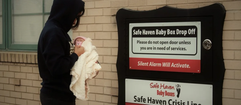 Una mujer con su bebé, frente a una caja refugio de Safe Haven