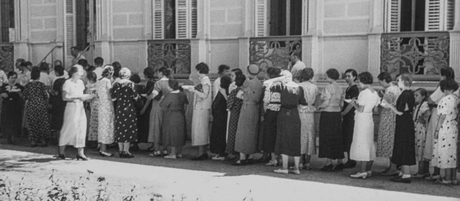 Grupo de personas esperando turno para obtener un plato de comida en los jardines de la embajada alemana de Madrid. Año 1936