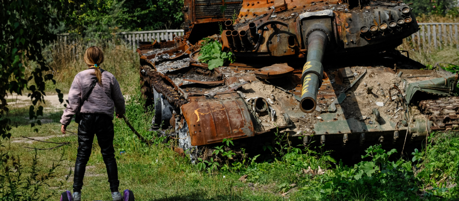 Una niña ucraniana juega cerca de los restos de un tanque de guerra