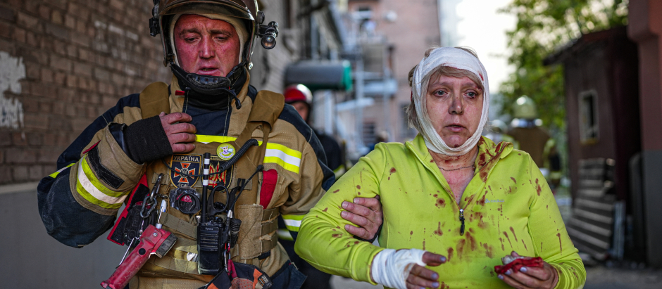 Un rescatista ayuda a una mujer herida por uno de los bombardeos rusos sobre Ucrania, este lunes