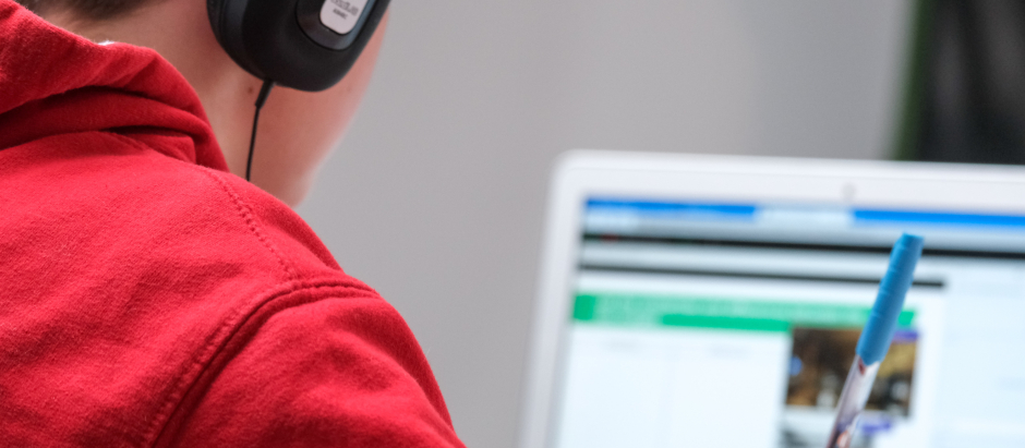 Un niño con auriculares, estudiando frente a su ordenador